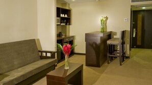 A modern hotel lobby with a sofa, a small table with a vase, a reception desk, and a chair. - Tryp San Jose Sabana (San José)