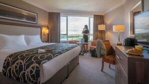 A hotel room with a large bed, a desk with a laptop, a chair, and a view of the outdoors. - Clayton Hotel Silver Springs (Cork)