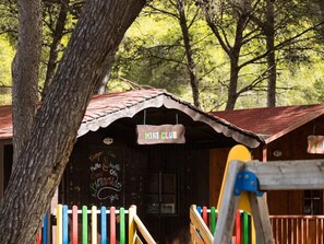 Un edificio rústico de madera con techo de lámina corrugada, una valla colorida y un letrero que dice 'MINI CLUB'.