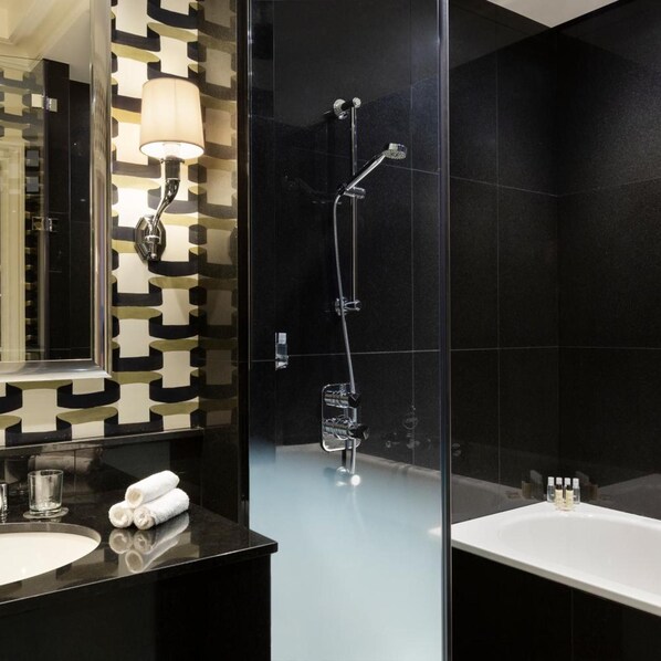 A modern bathroom with a glass-enclosed shower, a large mirror, and a black countertop. - Hotel Keppler (Paris)