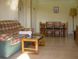 Una sala de estar con un sofá de cuadros, una mesa de centro de madera y un juego de sillas de madera.