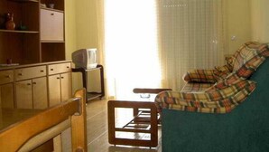 Un salon avec un canapé, des meubles en bois, un téléviseur et un lustre.
