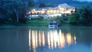 A large, multi-story hotel with a reflective pool in front, surrounded by lush greenery and mountains in the background. - Hunas Falls Hotel Kandy (Kandy)