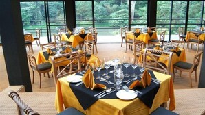 A dining area with tables set for service, large windows offering a view of greenery, and a modern interior design. - Hunas Falls Hotel Kandy (Kandy)