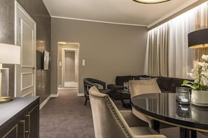 A modern hotel room with a dining area, a sofa, a round table, and a lamp. - Home Hotel Grand, Gjovik (Gjovik)