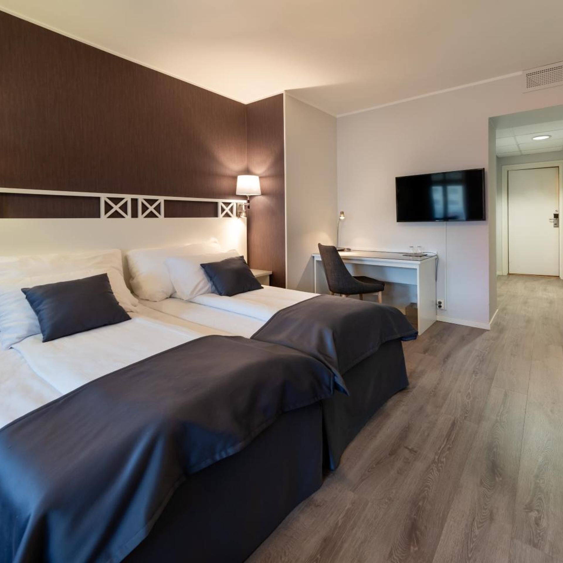 Una camera d'albergo con un letto grande, una scrivania, una sedia e una televisione.