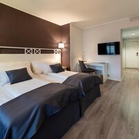 Una camera d'albergo con un letto grande, una scrivania, una sedia e una televisione.