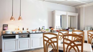 A modern kitchen with white cabinetry, a dining area with wooden chairs, and pendant lighting. - Home Hotel Grand, Gjovik (Gjovik)
