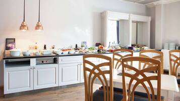 A modern kitchen with white cabinetry, a dining area with wooden chairs, and pendant lighting.