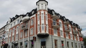 A multi-story building with a distinctive corner tower and balconies. - Home Hotel Grand, Gjovik (Gjovik)