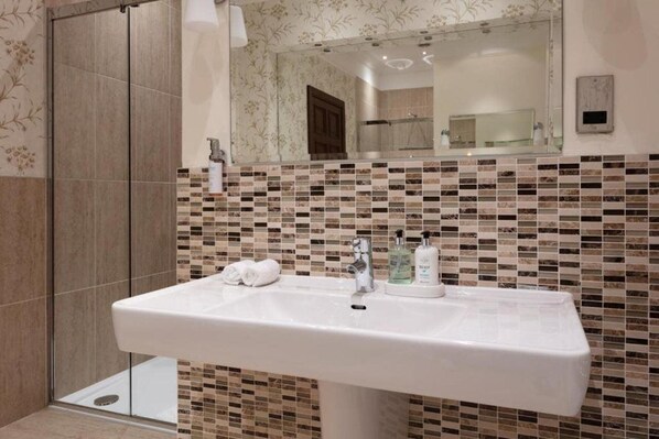 Un baño con lavamanos blanco, un espejo y salpicadero de azulejos.