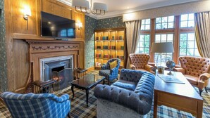 A traditional room with a fireplace, a bookshelf, plush seating, and a television. - Murrayshall Country Estate (Perth)