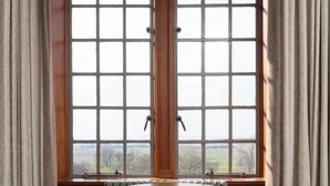 A room with a round wooden table, two plaid chairs, a window with a view, and a radiator. - Murrayshall Country Estate (Perth)