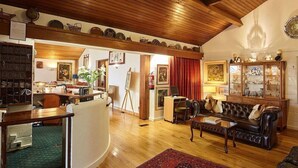 A spacious living room with a wooden ceiling, a leather sofa, a dining area with a table, and a kitchen visible through an open doorway. - Cedar Lodge Hotel and Restaurant (Carrigbyrne)