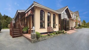 A two-story building with a beige facade, large arched windows, and a stone staircase leading to the entrance. - Cedar Lodge Hotel and Restaurant (Carrigbyrne)