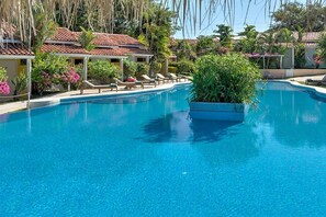 Ein klares, blaues Schwimmbecken mit Liegestühlen und einer Topfpflanze.