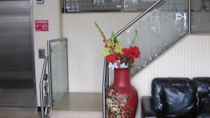 Een trap met een rode vaas vol bloemen, een zwarte leren bank en een roestvrijstalen lift.