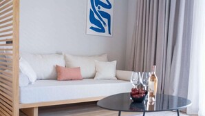 A modern living room with a sofa, a glass coffee table, and a decorative wall piece. - Domes Noruz Kassandra - Adults-only (Kassandra)
