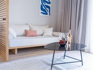 A modern living room with a sofa, a glass coffee table, and a decorative wall piece. - Domes Noruz Kassandra - Adults-only (Kassandra)