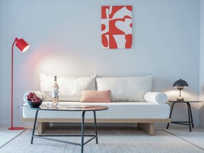 A modern living room with a sofa, a small round table, a floor lamp, and a wall art piece. - Domes Noruz Kassandra - Adults-only (Kassandra)