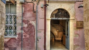 A building entrance with a wrought iron gate, a staircase leading inside, and a sign reading "ENIA."
