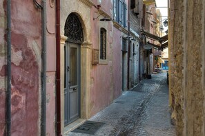 A narrow cobblestone street lined with historic buildings, featuring arched doorways and traditional architecture. - Elia Zampeliou - Adults Only (Chania)