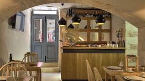 A cozy dining area with wooden furniture, a bar with bottles, and a stone wall.