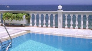 A swimming pool with a white balustrade and a view of the ocean. - Ostria Seaside Studios and Apartments (Chios)