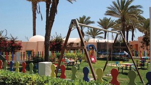 A playground with swings and slides, surrounded by palm trees and colorful fences. - Oasis Marine (Zarzis)
