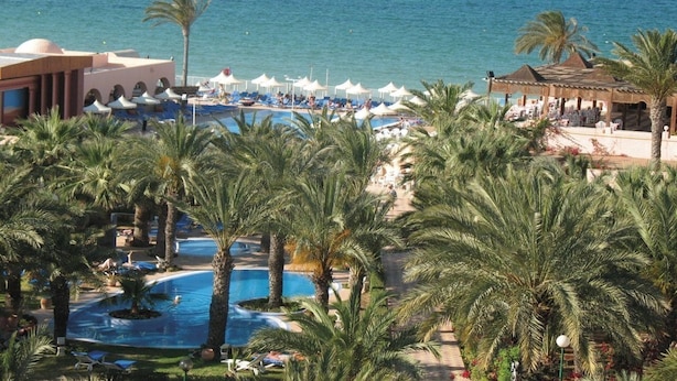 A resort with a pool area, palm trees, and a view of the sea. - Oasis Marine (Zarzis)