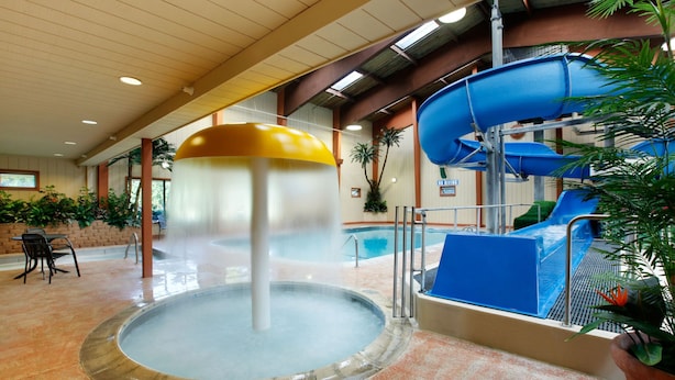 Ein Indoor-Wasserpark mit Whirlpool, blauer Rutsche und Schwimmbecken.