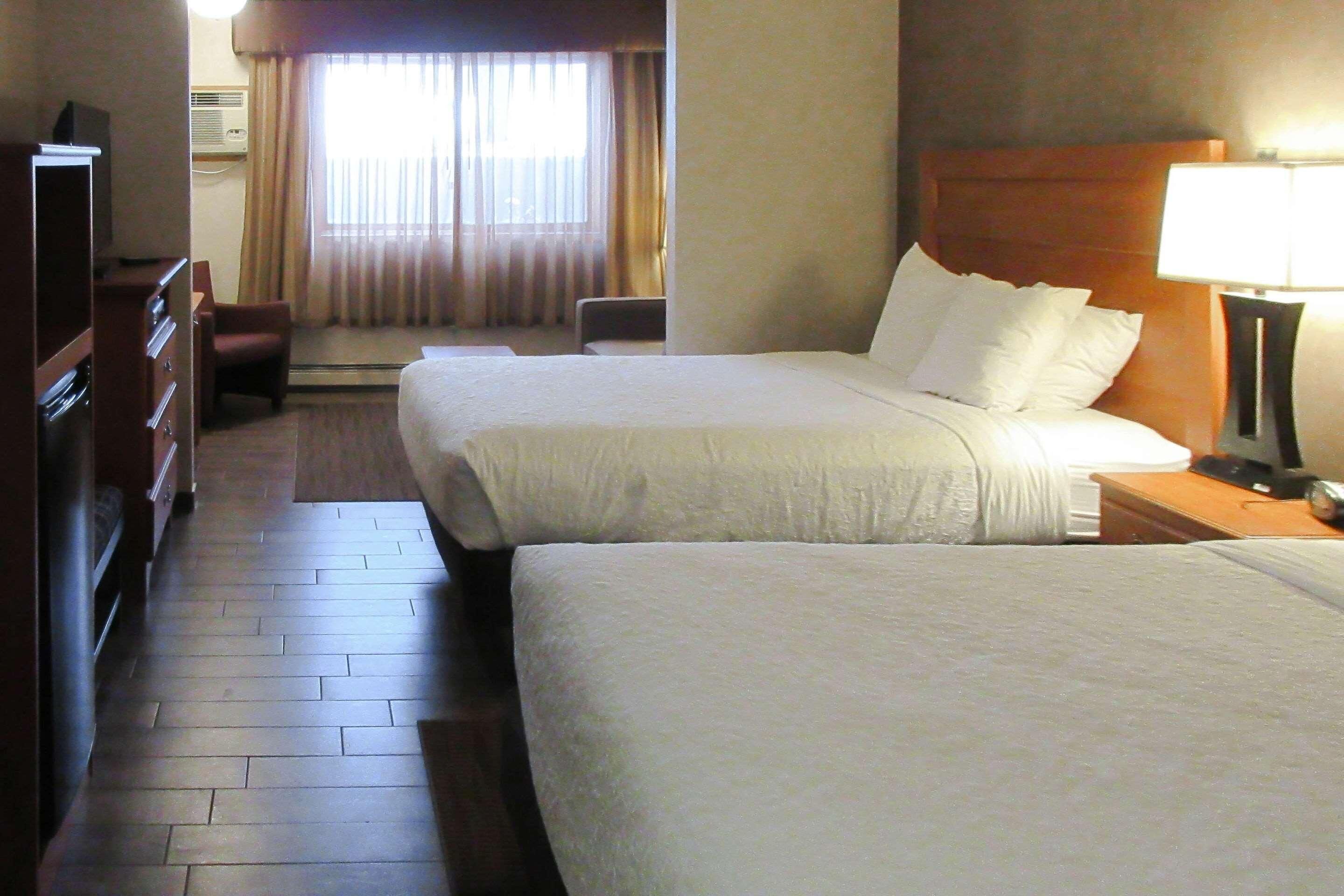 Une chambre d’hôtel avec deux lits, un bureau, une chaise et un téléviseur.