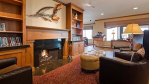 Ein gemütliches Wohnzimmer mit Kamin, Ledersitzmöbeln, einem Couchtisch und einem Bücherregal.