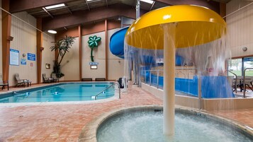 Una piscina interior con tobogán y jacuzzi.