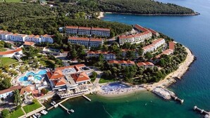 Vue aérienne d’une station balnéaire comprenant plusieurs bâtiments d’hôtel, une piscine et une plage.