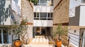 A multi-level building with a staircase, potted plants, and a number '73' sign. - Comfort Vaggelis Studios (Hersonissos)