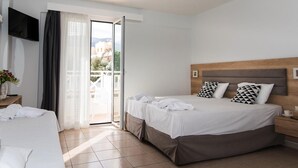A hotel room with a bed, a TV mounted on the wall, and a balcony with a view. - Comfort Vaggelis Studios (Hersonissos)