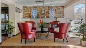A lobby with a stone wall, red leather chairs, a round table, and a fireplace. - The Capitol Hotel, Ascend Hotel Collection (Hartford)