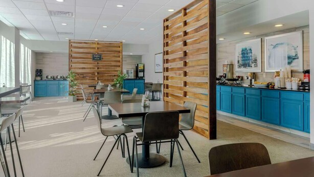 A modern office space with a central dining area, blue cabinets, and wooden partitions. - The Capitol Hotel, Ascend Hotel Collection (Hartford)