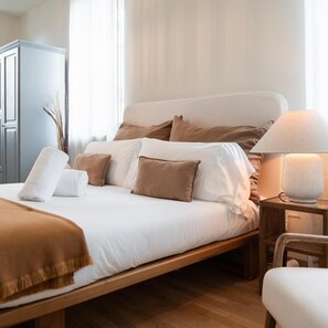 A neatly made bed with a wooden frame, a bedside table with a lamp, and a chair. - San Marco (Verona)