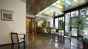 Vestíbulo de hotel con piso pulido, una recepción y zonas de estar.
