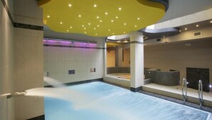 Una amplia piscina cubierta con un diseño moderno, que incluye un techo amarillo y una zona de jacuzzi.
