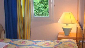 A bedroom with a bed, a window with curtains, and a bedside lamp. - Gerekos Apartments (Corfu)