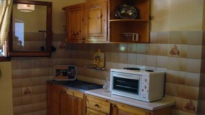 A compact kitchen with wooden cabinets, a microwave, and a small sink. - Gerekos Apartments (Corfu)