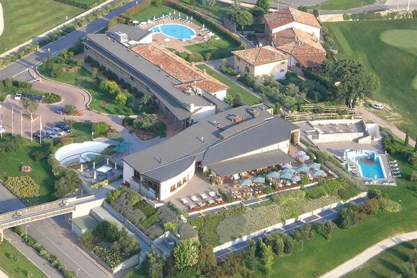 Vue aérienne d’un hôtel doté d’une piscine, de plusieurs bâtiments et d’un jardin aménagé.