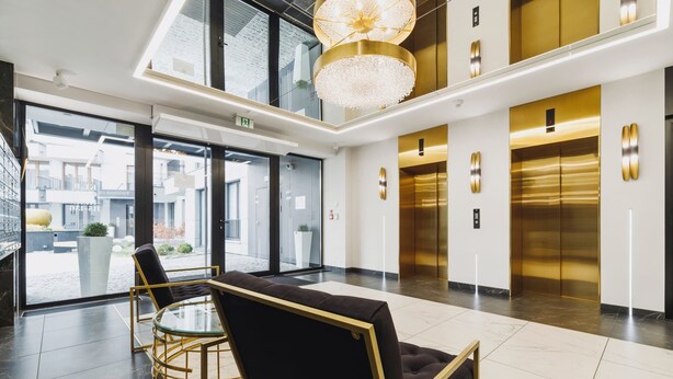 A modern lobby with a glass partition, two elevators, and a chandelier. - Stylish Apartment with 2 Bedrooms | Parking and Balcony (Kraków)