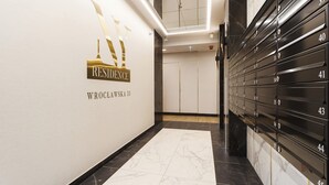 A hallway with a 'Residence' sign, numbered storage lockers, and a marble floor. - Stylish Apartment with 2 Bedrooms | Parking and Balcony (Kraków)