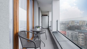 A balcony with a table and chairs, large windows, and a city view. - Stylish Apartment with 2 Bedrooms | Parking and Balcony (Kraków)