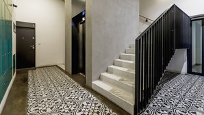 Un intérieur moderne avec un sol à motifs, un escalier doté de rampes noires et une porte portant le numéro « 1 ».