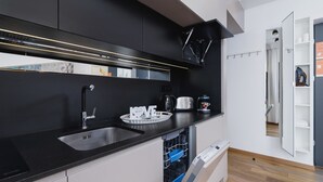 Une cuisine moderne avec des meubles de couleur noire, un évier en acier inoxydable et un lave-vaisselle.